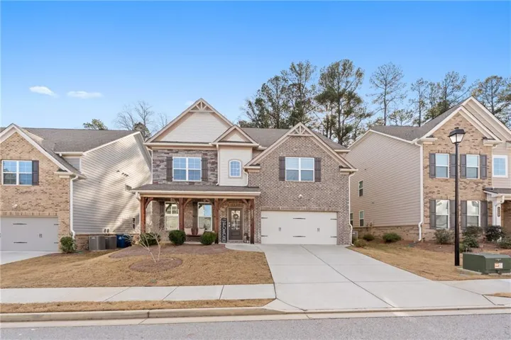 Craftsman house featuring covered porch, driveway, brick siding, and an attached garage