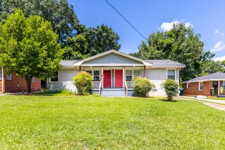 Light gray exterior with red entry doors, gray porch railings, and a green lawn