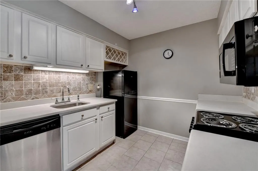 Kitchen with white cabinetry, a sink, tasteful backsplash, and black appliances