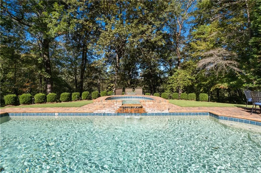 Outdoor pool with a patio area, an in-ground hot tub, and view of wooded area Outdoor pool with a patio area, an in-ground hot tub, and view of wooded area