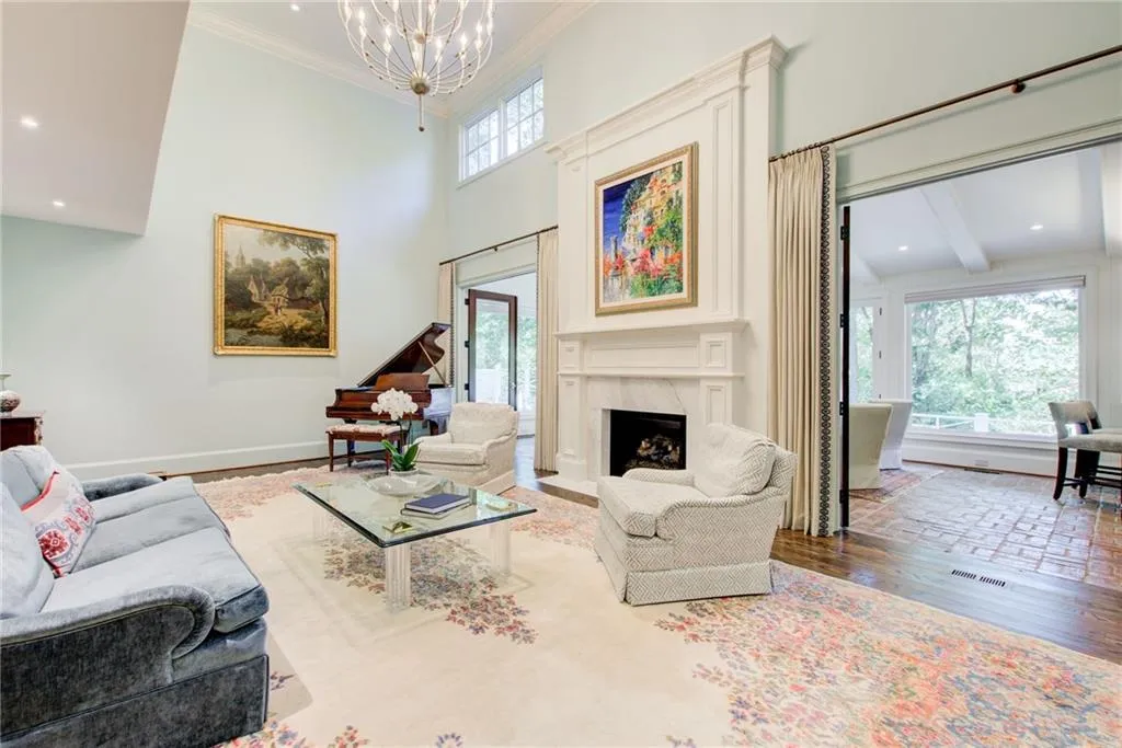 Living area featuring hardwood / wood-style flooring, a fireplace, ornamental molding, a towering ceiling, and recessed lighting Living area featuring hardwood / wood-style flooring, a fireplace, ornamental molding, a towering ceiling, and recessed lighting