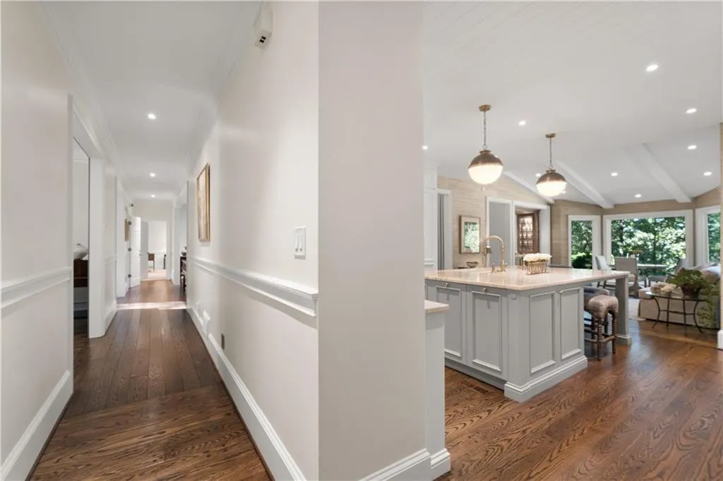 Hallway with dark wood finished floors, recessed lighting, crown molding, and beamed ceiling leads to the dining room and primary on main at the end of the hall. Hallway with dark wood finished floors, recessed lighting, crown molding, and beamed ceiling leads to the dining room and primary on main at the end of the hall.