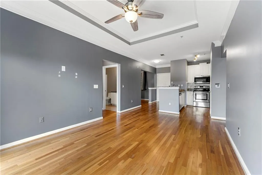 Unfurnished living room with ornamental molding, a tray ceiling, dark wood-type flooring, and ceiling fan