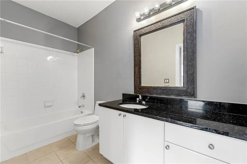 Bathroom featuring shower / bath combination, light tile patterned floors, vanity, and a textured ceiling