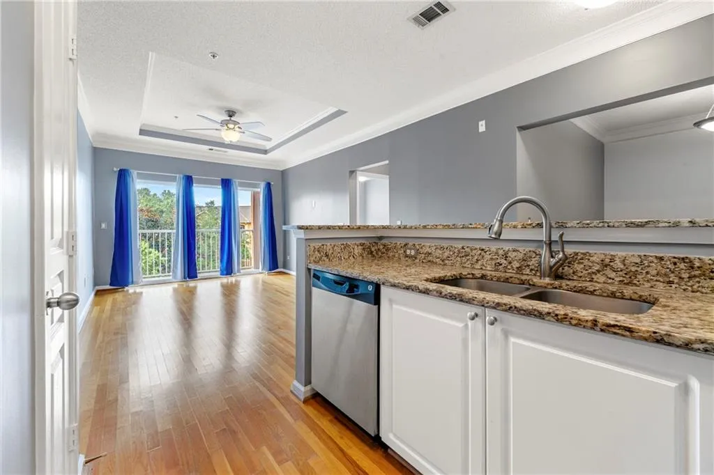 Kitchen with light stone counters, white cabinets, ceiling fan, light wood finished floors, and dishwasher