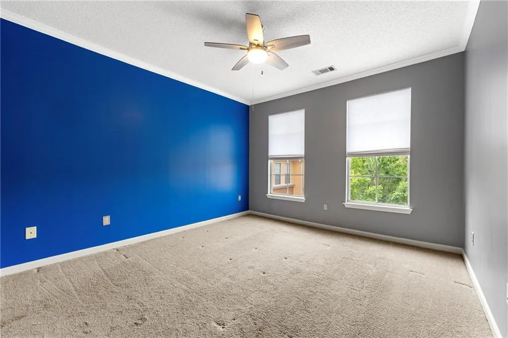 Empty room with ornamental molding, a textured ceiling, carpet flooring, and ceiling fan