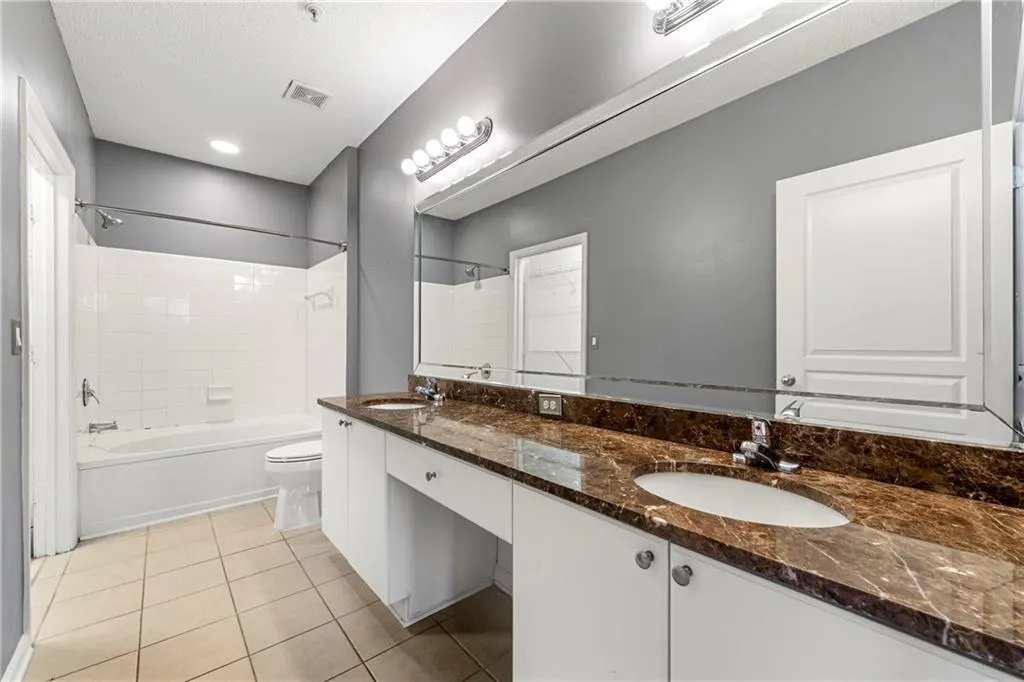 Full bathroom featuring bathtub / shower combination, light tile patterned floors, and double vanity