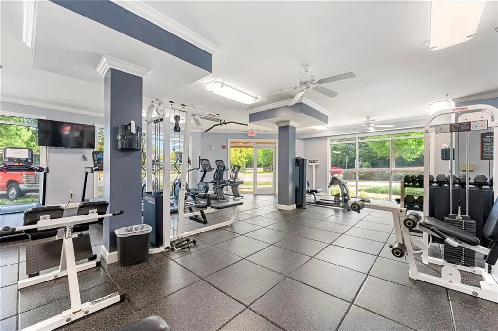 Gym featuring plenty of natural light, ceiling fan, and crown molding
