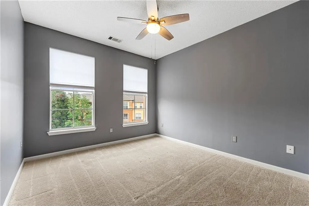 Empty room featuring light colored carpet, a textured ceiling, and a ceiling fan