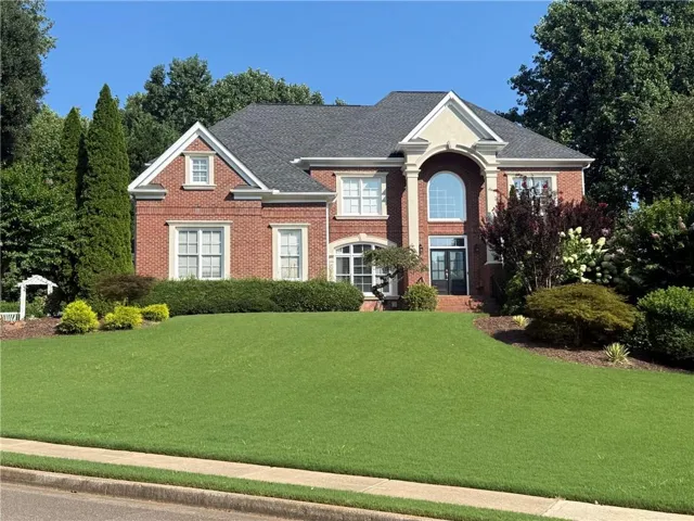 Traditional brick residence featuring a prominent arched window and a striking front entrance with double doors