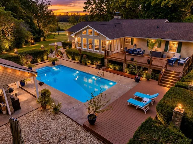 Expansive outdoor living area featuring a large swimming pool, multi-level composite decking, and a covered patio structure
