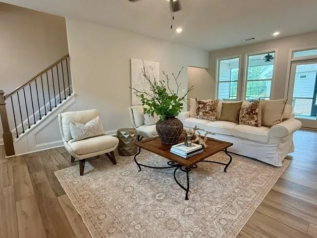 Wood-finish flooring throughout, modern staircase with black iron spindles, recessed lighting, and ceiling fan