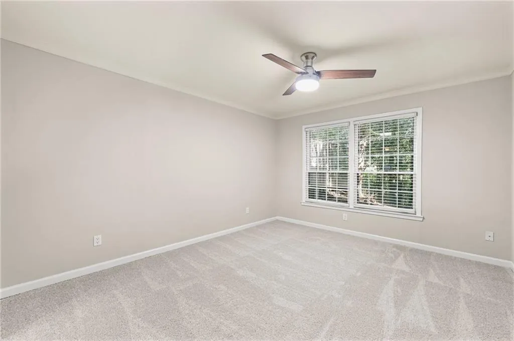 New carpet, soft grey wall paint, multi-pane window, and a ceiling fan with integrated lighting