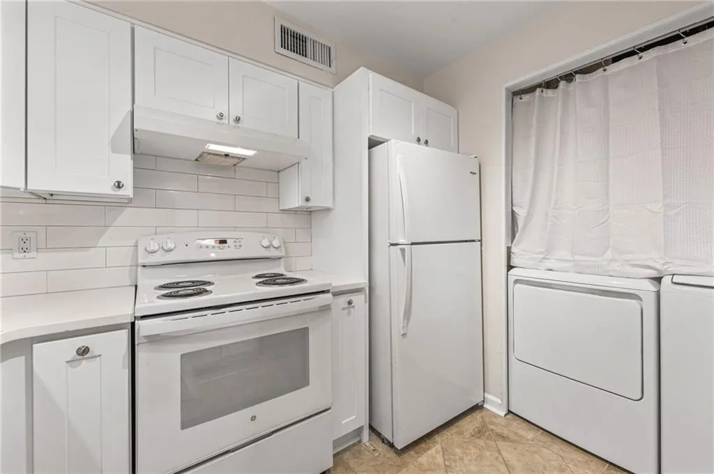 White cabinetry, subway tile backsplash, white range, white refrigerator, and compact laundry appliances