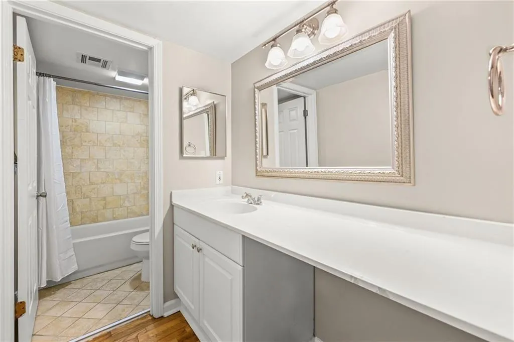 White vanity with integrated sink, expansive countertop, framed mirror, and three-light vanity fixture
