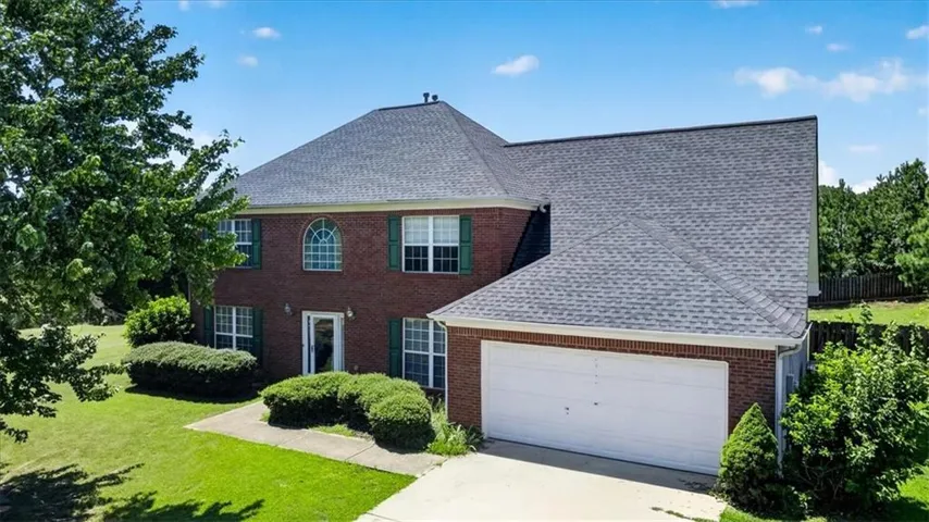 Brick exterior with shuttered windows, an attached two-car garage, and a gabled roofline