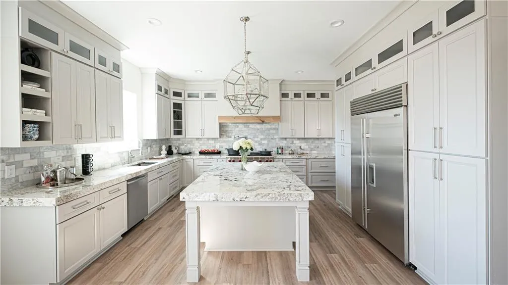 Kitchen with a kitchen island, stainless steel appliances, light wood-style flooring, and white cabinetry