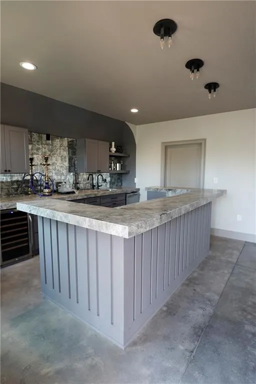 Dual tone kitchen featuring light countertops, concrete flooring, open shelves, beverage cooler, and two tone color scheme