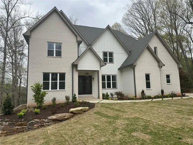 View of front facade with board and batten siding, a front yard, and brick siding