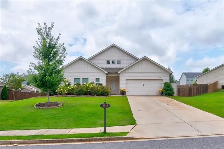 Contemporary exterior with board and batten siding, attached two-car garage, concrete driveway, and mature landscaping