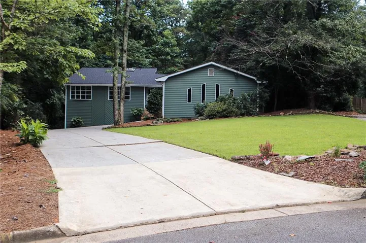 Green siding exterior with a dark shingled roof