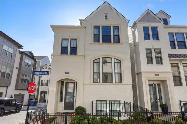 White brick facade with black-framed windows, an arched entry, and a gabled roofline