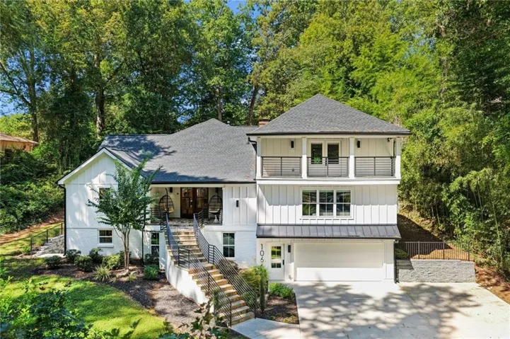 Contemporary exterior with white board-and-batten siding, a prominent staircase with metal railings, a two-car garage, and upper-level balconies with metal railings