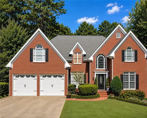 Brick exterior with gabled roof lines, arched windows, and a two-car garage