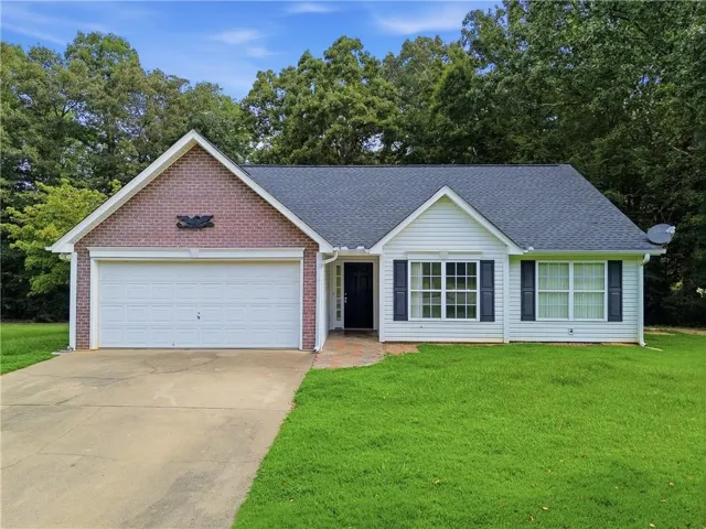 Brick and siding exterior with a dark shingle roof, attached garage, and a concrete driveway