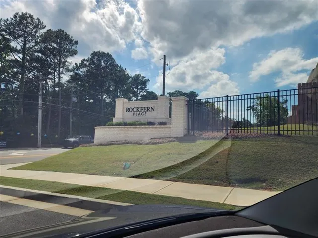 Entry monument with "ROCKFERN PLACE" signage, brick-clad base, and wrought iron-style fencing