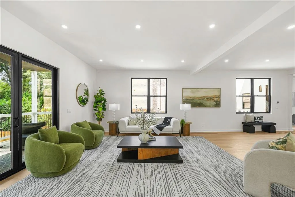 Recessed lighting, wood-finish flooring, white walls, and large black-framed windows create a bright, open living space