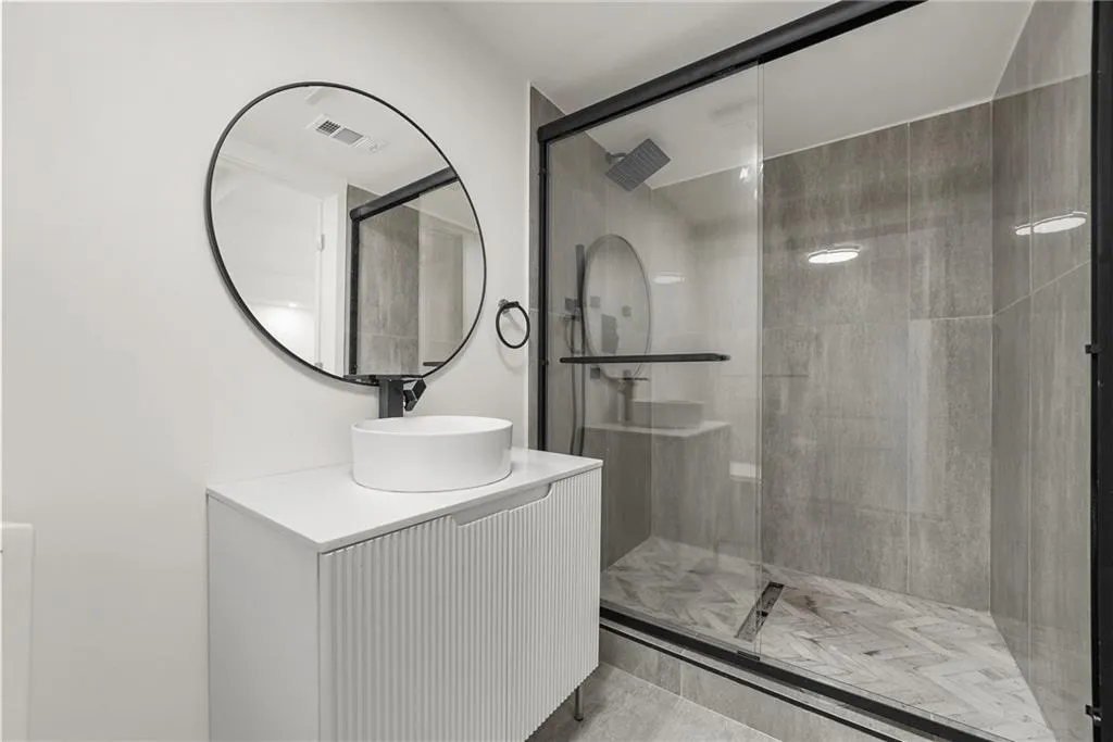 Modern floating vanity with a circular vessel sink, wall-mounted faucet, and a large round mirror
