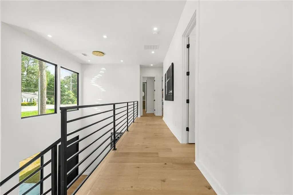 Wide plank wood-finish flooring, white walls, recessed lighting, and a contemporary chandelier