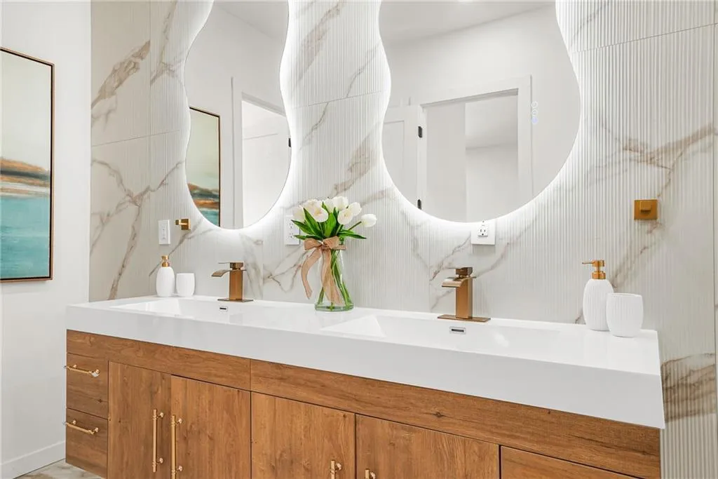 Double vanity with integrated sinks, wood-finish cabinetry, and gold-tone hardware