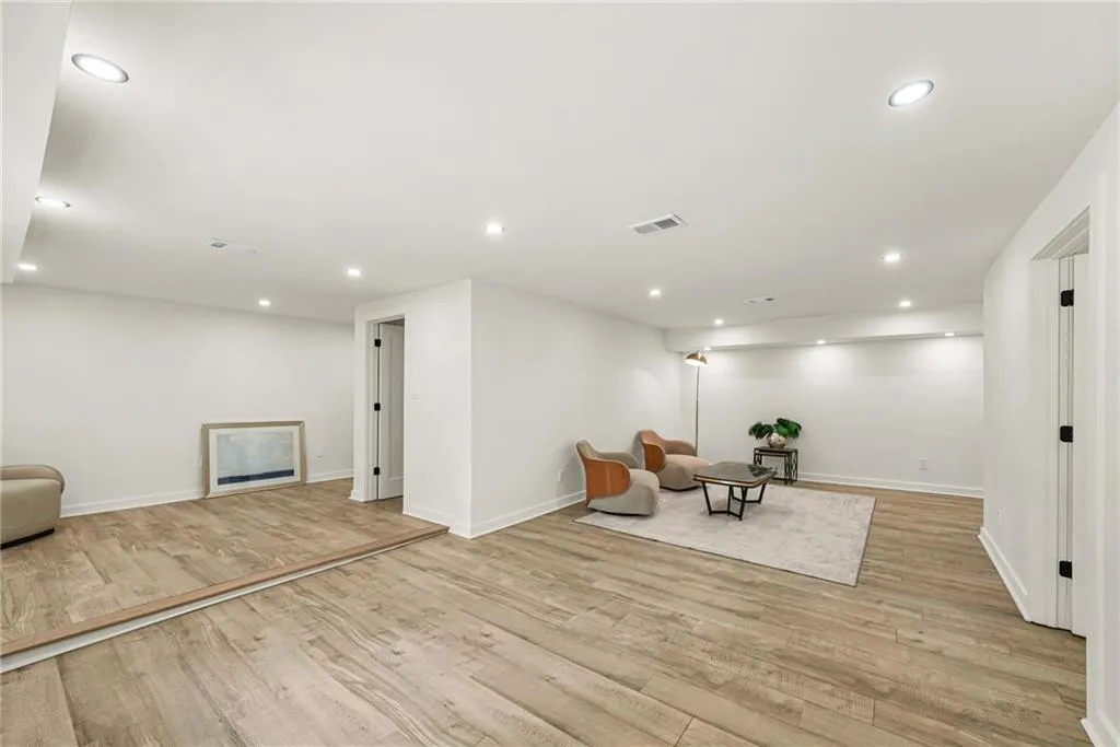 Spacious room with recessed lighting, light wood-finish flooring, white walls, and a white trim