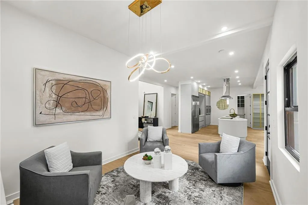 Recessed lighting, wood-finish flooring, a modern chandelier, and a kitchen with an island and stainless steel appliances