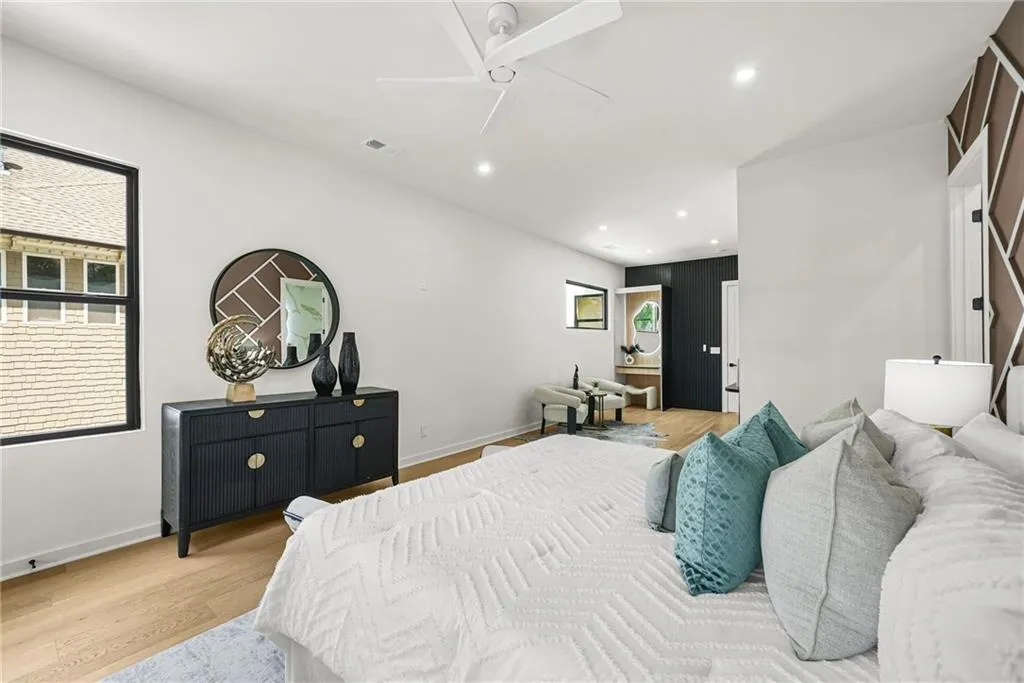 Vaulted ceiling with a flush-mount ceiling fan, recessed lighting, wood-finish flooring, and a large window with black trim
