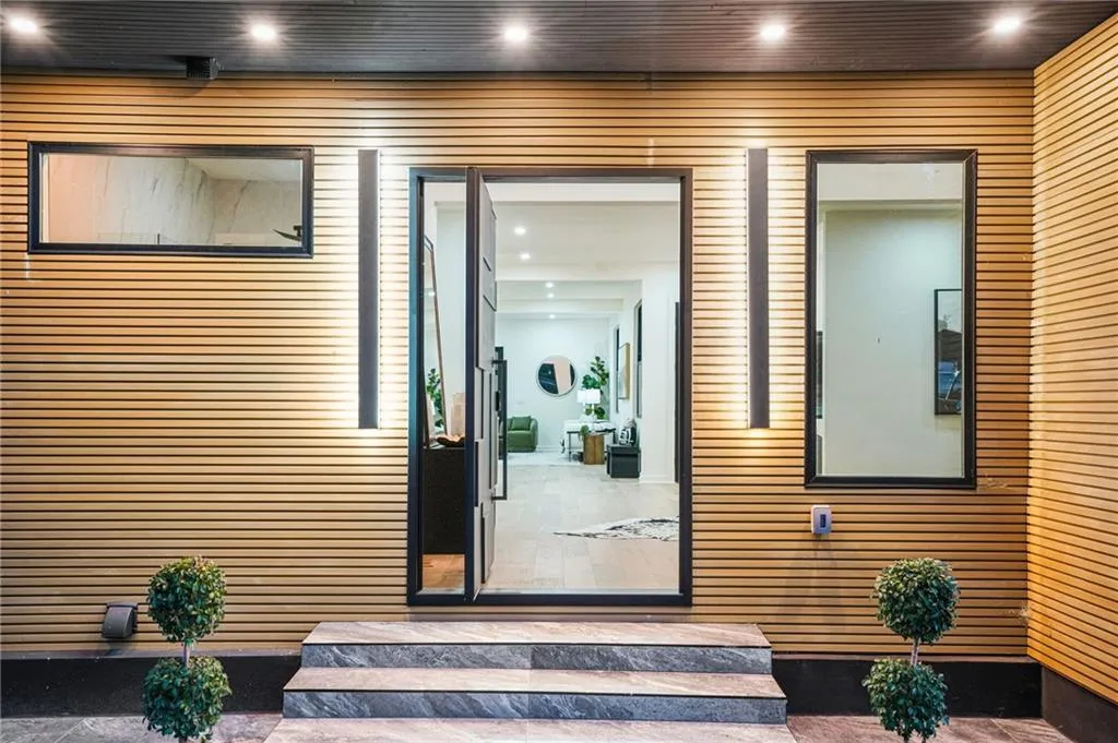 Contemporary wood-slat exterior with recessed lighting, a modern entry door, and stone steps