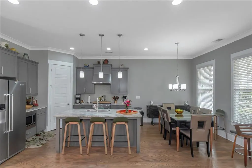 Kitchen with gray cabinets, a kitchen bar, an inviting chandelier, stainless steel appliances, and an island with sink