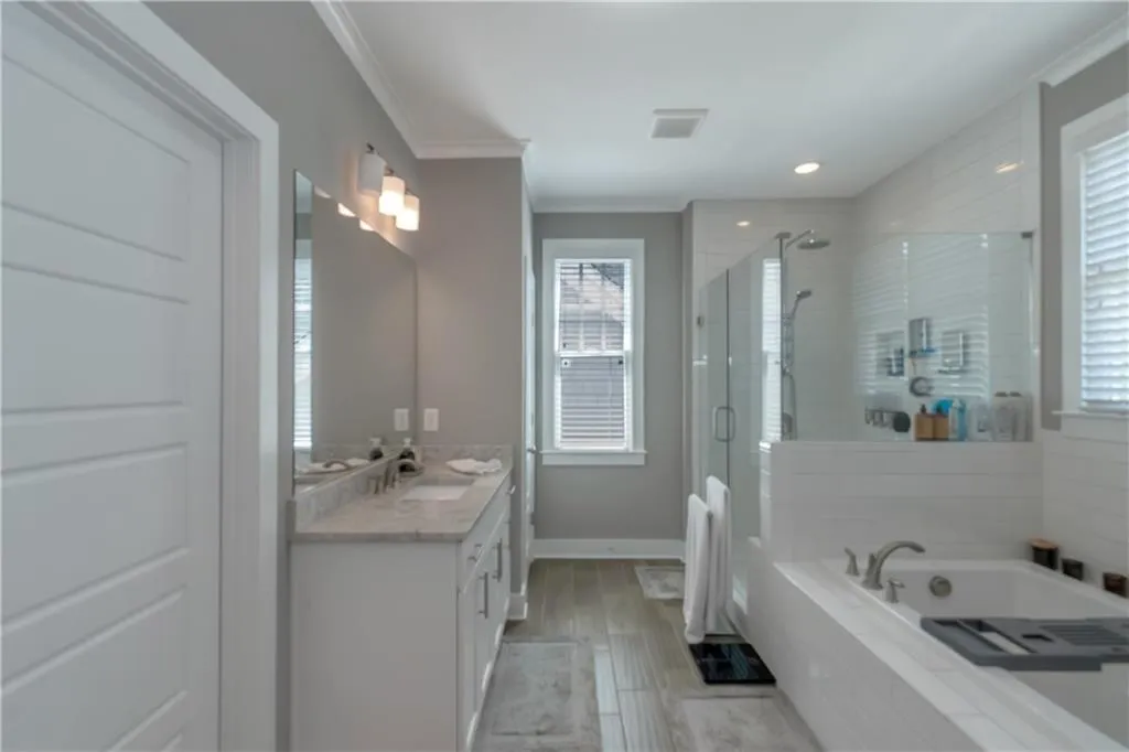 Full bathroom with a garden tub, visible vents, crown molding, a shower stall, and vanity