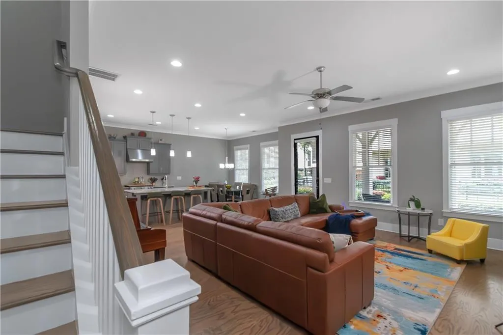 Living area with a ceiling fan, wood finished floors, stairway, ornamental molding, and recessed lighting