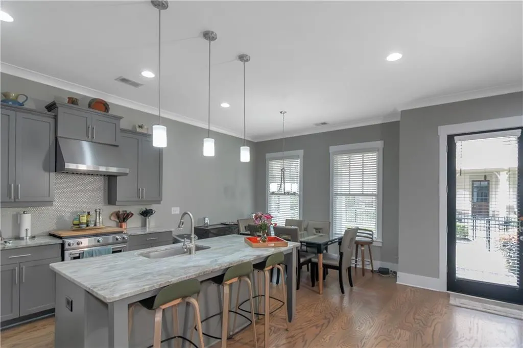 Kitchen featuring a sink, stainless steel range with electric stovetop, wood finished floors, under cabinet range hood, and gray cabinetry
