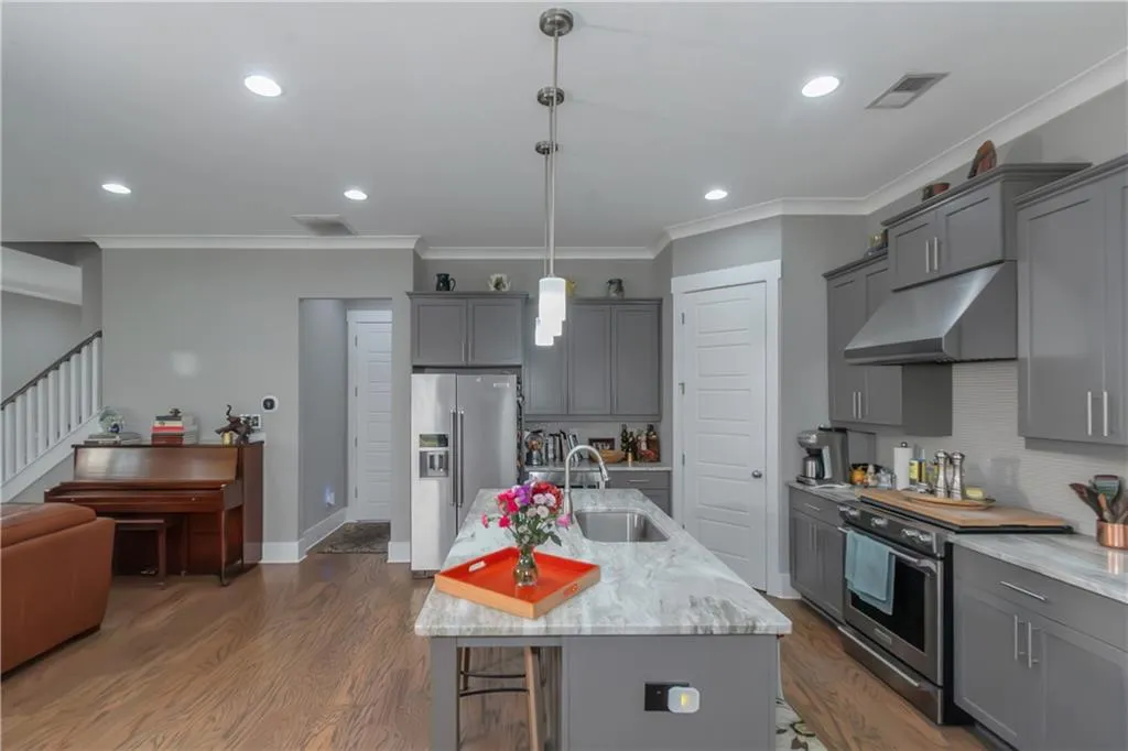 Kitchen featuring under cabinet range hood, stainless steel appliances, gray cabinets, and a sink
