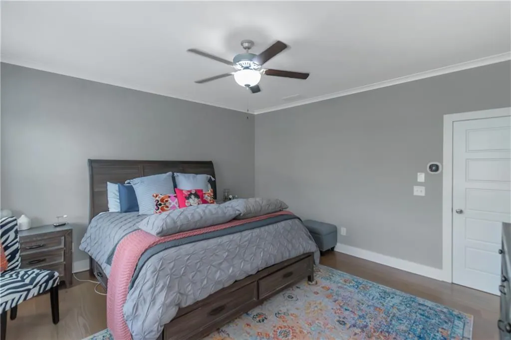 Bedroom with ceiling fan, baseboards, ornamental molding, and wood finished floors
