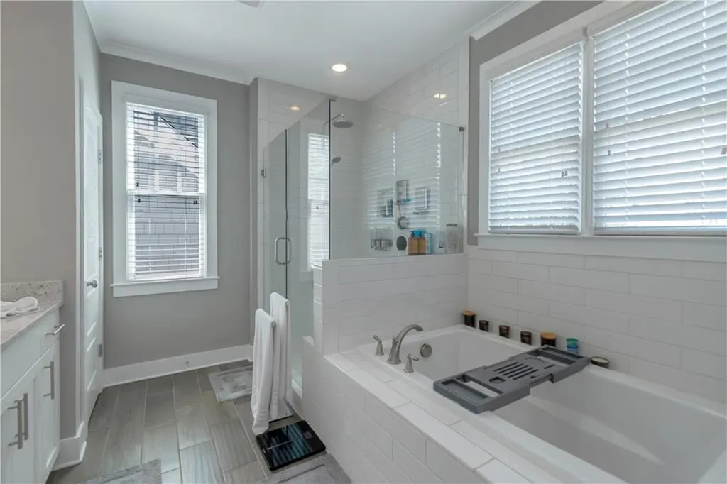 Bathroom with a garden tub, a stall shower, vanity, baseboards, and recessed lighting