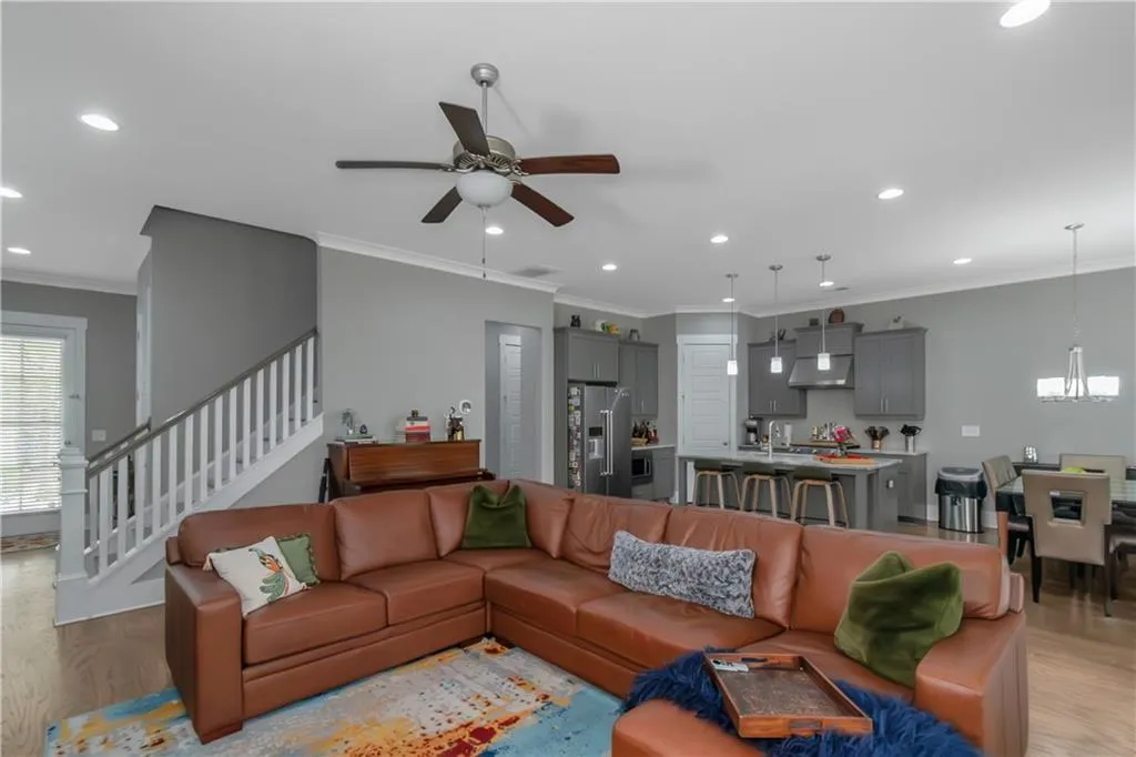 Living room featuring stairway, recessed lighting, ceiling fan with notable chandelier, and light wood-type flooring