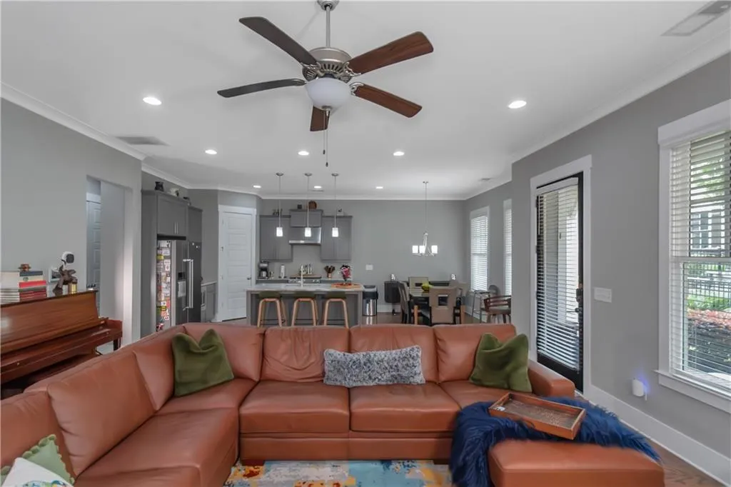 Living room with baseboards, a ceiling fan, recessed lighting, and ornamental molding