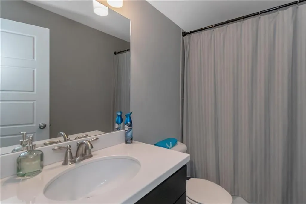 Full bath with toilet, curtained shower, and vanity