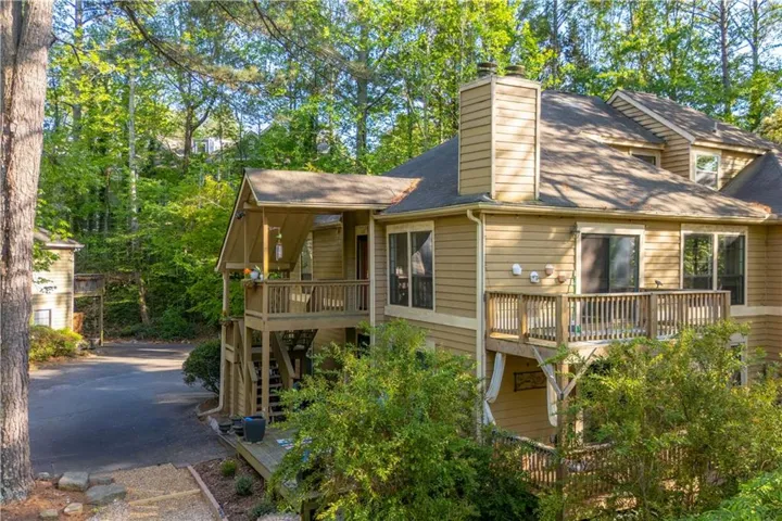 This property features a multi-level exterior with a light brown siding, a prominent chimney, and a dark shingled roof