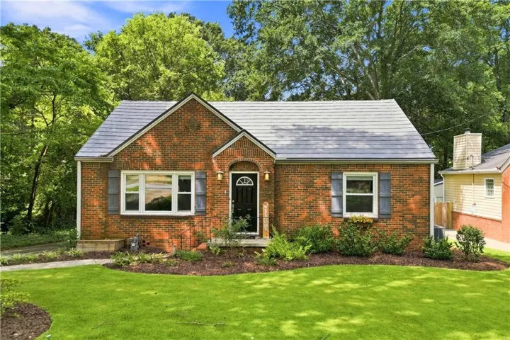 Brick exterior with a gray shingle roof, arched entryway, and decorative window shutters